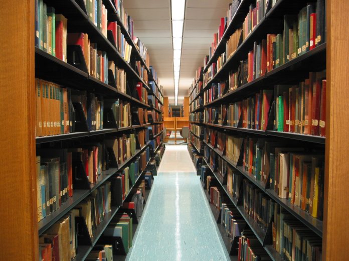 A view of the stacks in the main library at Connecticut College. With a line of lights parrel to the stacks.