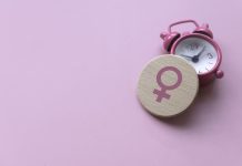 Mind and menopause care: What to expect Menopause concept. Women symbol over a watch. Healthcare and medical for women. Pink background with copy space.