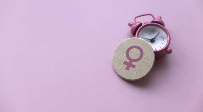 Menopause concept. Women symbol over a watch. Healthcare and medical for women. Pink background with copy space.