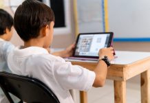 Children’s in‑school mental health programme cuts over 900 CAMHS referrals in 6 months boy using digital device in school classroom.