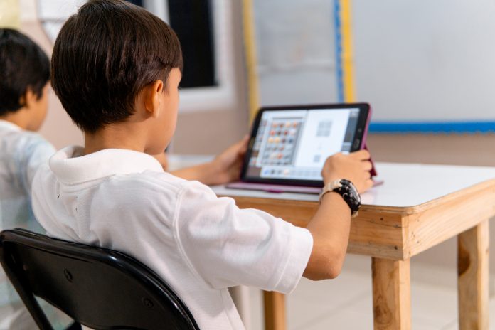 boy using digital device in school classroom.