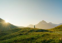 Woman hiking through the meadow in Swiss Alps in morning