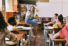 Fun, happy and excited teacher talking to students in school classroom with group of learning children. Confident, friendly and cool woman asking diverse young kids education questions in study class