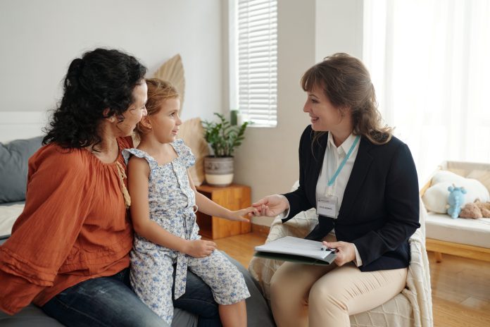 Social Worker Visiting To Single Mom At Home Social worker talking to little girl and her mom during her visit