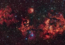 This image shows a cloud of gas and dust, shaped like a cosmic bat. The image was obtained mostly in visible light with the VLT Survey Telescope (VST), hosted at ESO’s Paranal Observatory in Chile. The intense red glow comes from hydrogen atoms ionised by the intense radiation of young stars within the cloud. The image also includes additional infrared data captured by ESO’s Visible and Infrared Survey Telescope for Astronomy (VISTA), also at Paranal. The most prominent clouds here are RCW 94, which represents the right wing of the bat, and RCW 95, which forms the body, while the other parts of the bat have no official designation. Credit: ESO/VPHAS+ team/VVV team