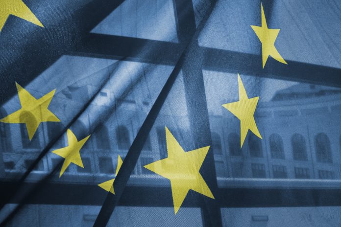 A transparent European Union flag obscures partly a building