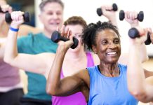 Why strength training is critical to healthy aging Close-up of a senior African-American woman in her 60s enjoying an exercise class. She is with a multiracial group of mature adults sitting on fitness balls and lifting hand weights.