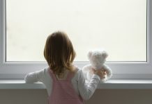 Building blocks for policy change: Upholding the rights of all children affected by parental imprisonment Little girl holding white teddy bear and standing alone at window and looking out from home. Back view. Waiting concept. Close up.