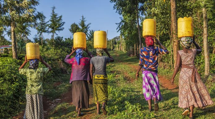 African women carrying water to their village, Kenya, Africa. African women and also children often walk long distances to bring back containers of water.