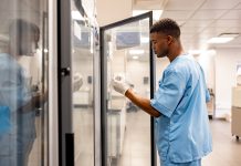 The vaccine cold chain: A fragile link in global health infrastructure African American healthcare worker working at the laboratory and taking medicines out of a fridge - hospital concepts