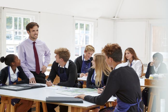 Teenage Students Listening To Teacher In Art Class Teenage Students Listening To Teacher In Art Class