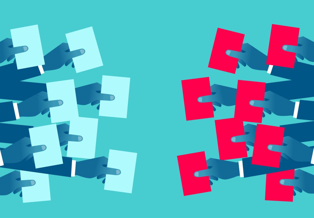 Two groups of hands holding ballots of different colors