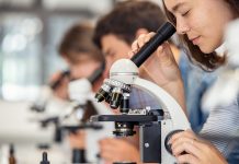 High school girl looking through microscope at school
