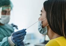 Medical worker wearing personal protective equipment doing corona virus swab on female patient - Covid19 test and health care concept