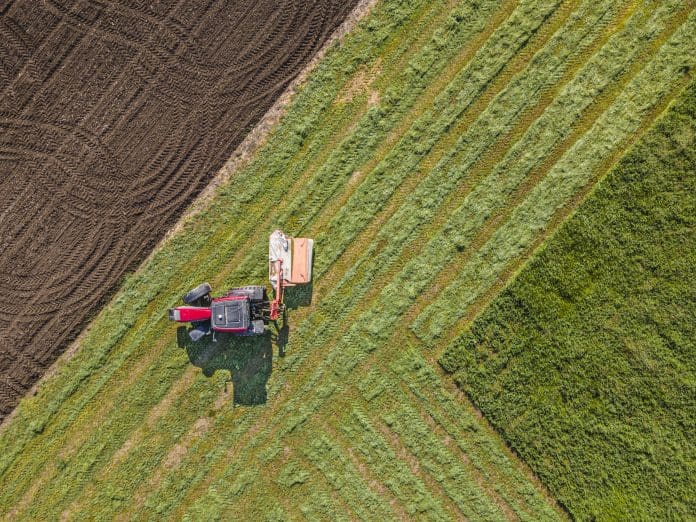 Aerial view of tractor mowing alfalfa. Springtime agriculture.