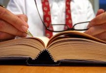 Business man researching and making notes from a book