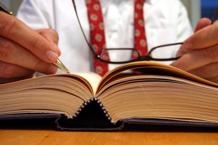 Business man researching and making notes from a book