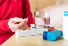 Senior woman taking medication from daily pill box