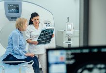 A woman is sitting in a hospital room with a doctor looking at a medical image