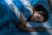 Pretty young woman sleeping restful in bed at morning with sun ray coming in room