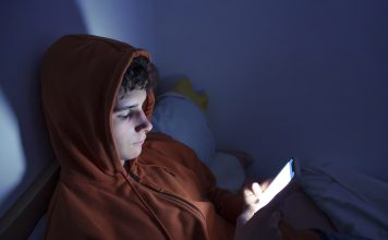 eenager using a smartphone lying in bed late at night