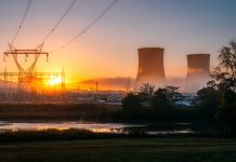 Sunrise behind Cooling Towers and Lattice Towers of a Nuclear Power Plant
