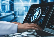 Close up of doctor working and typing at laptop and tablet display heart screen at laboratory with blurring background. Medical worker checking at medical and preparing for heart surgery. Remedial.