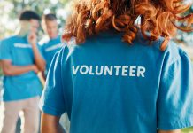Volunteer, shirt and back of woman in park for recycle program, earth day or social responsibility. Environment, climate change and ngo with person in nature for non profit, cleaning or charity