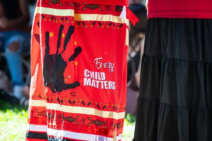 Sacramento, CA, U.S.A. - Sept. 26, 2025: Close up of a skirt combining an Every Child Matter message with a Missing and Murdered handprint symbol on red taken at the State Capitol public park area.