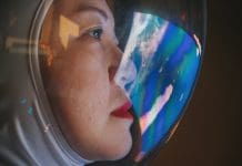 Asian chinese mid adult female astronaut looking at earth through window from spaceship at outer space