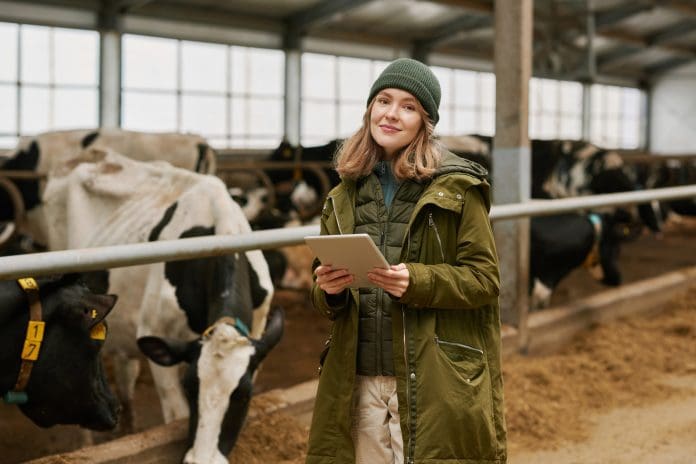 Portrait of young farmer using digital tablet to watch information about each milk cow during her work on farm