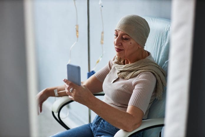 Side view senior woman with IV drip and using smartphone Side view portrait of senior woman sitting in comfortable chair with IV drip and using smartphone
