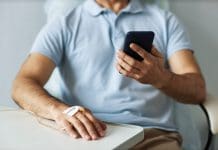 Closeup of unrecognizable man using smartphone during chemotherapy treatment, copy space