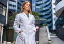 Smiling female surgeon standing outdoors while looking away. A female healthcare worker leaving the house in her uniform.