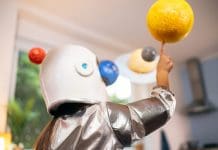 Girl in a space suit playing at home, exploring and learning about planets, imagining space travel.
